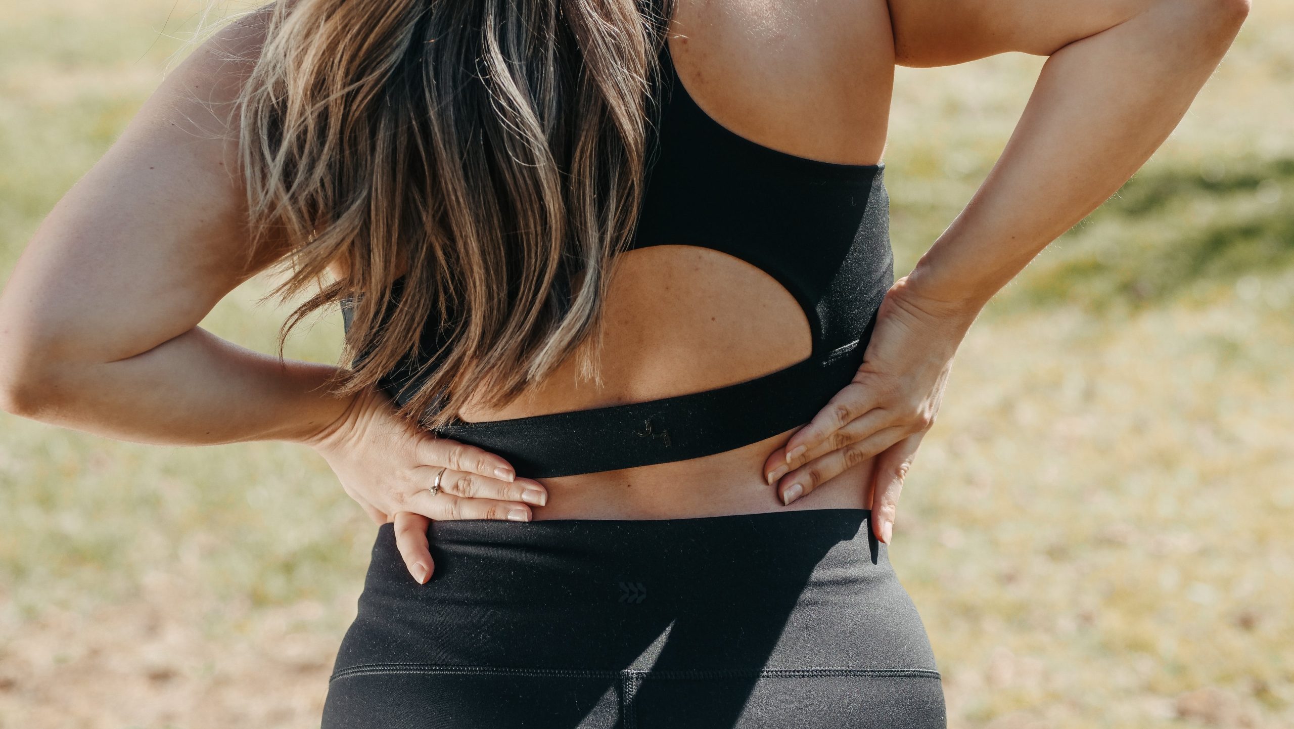a woman with her hands on her lower back pain after a workout