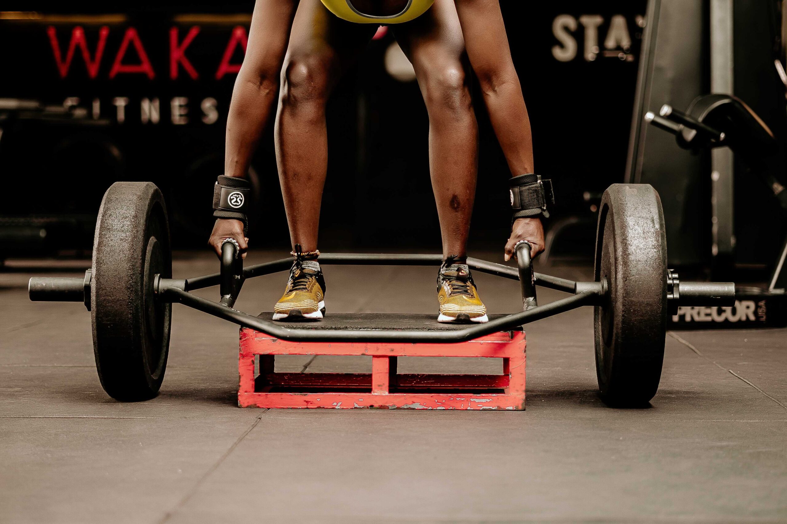 A person standing on a lift ready to raise an Olympic deadlift bar