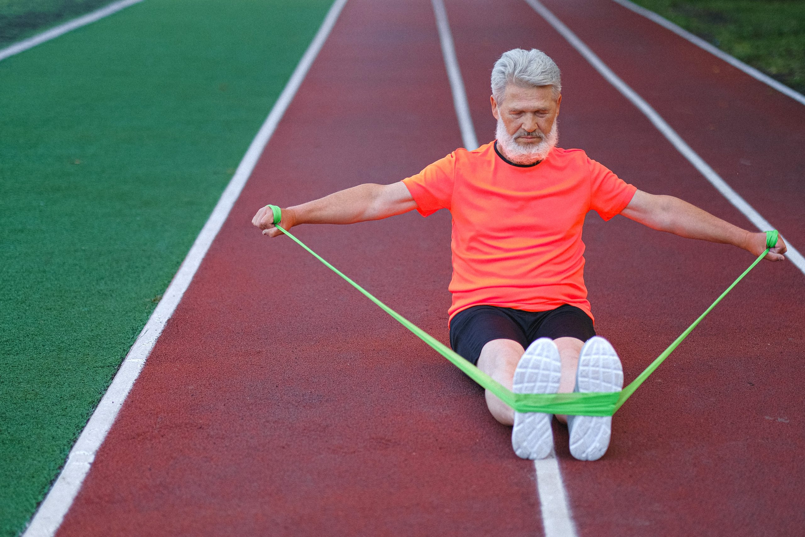 man using resistance band to exercise and stretch on a track
