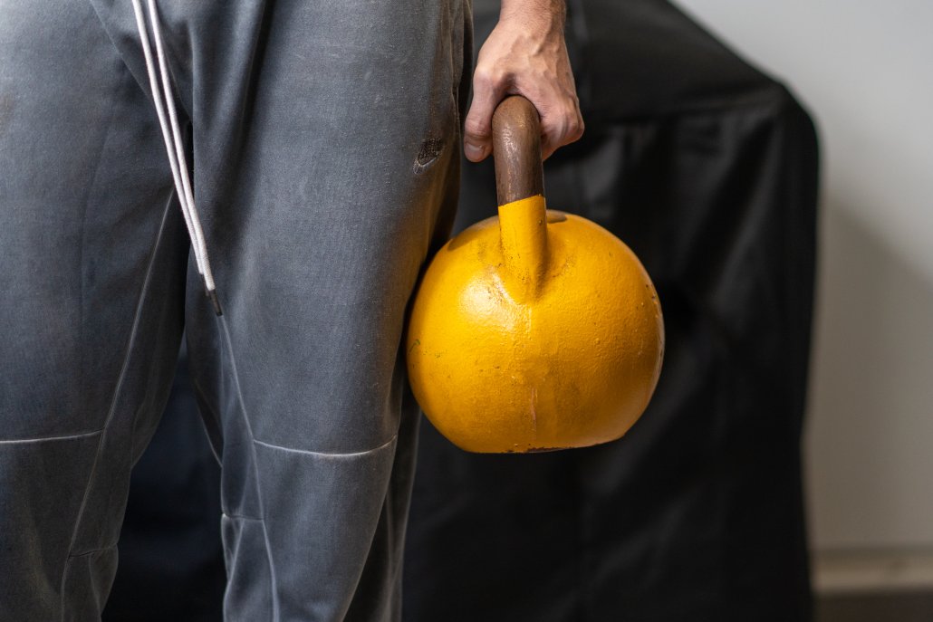 Cropped man holding yellow kettlebell for lower back exercises