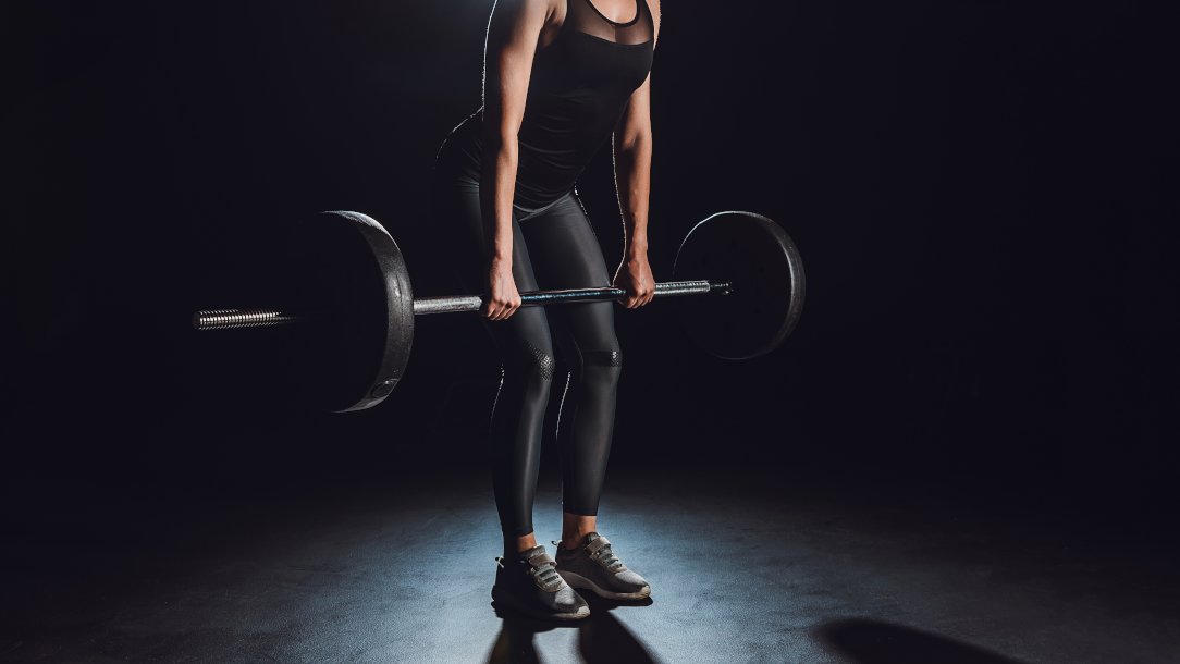 cropped image of female athlete doing a Deadlift for a Back or Leg Exercise at gym, black background
