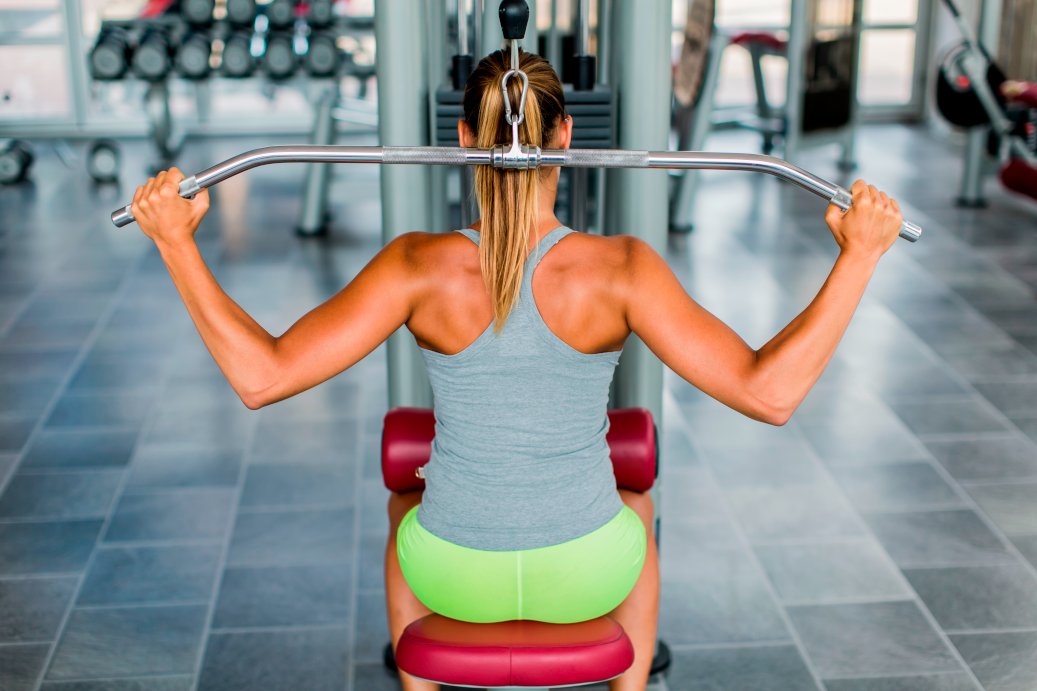Pretty young woman training with compound back movements in the gym