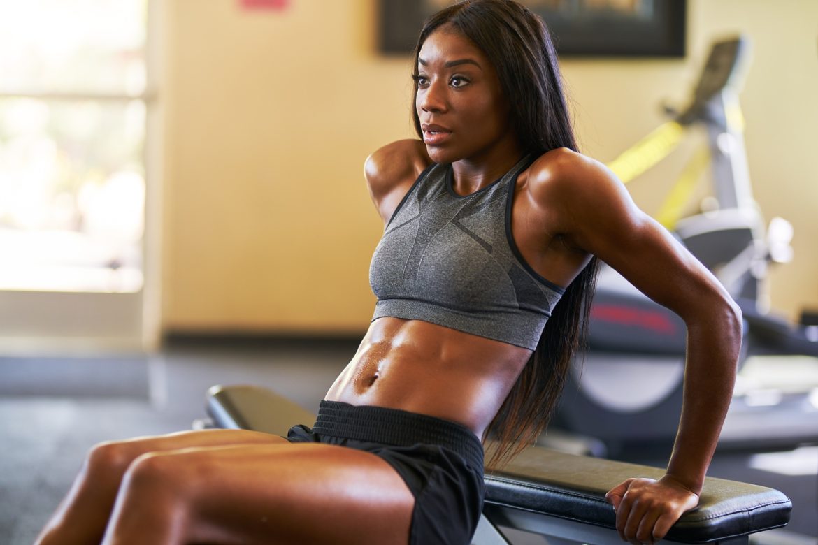 fit african american woman working out and stretching in gym